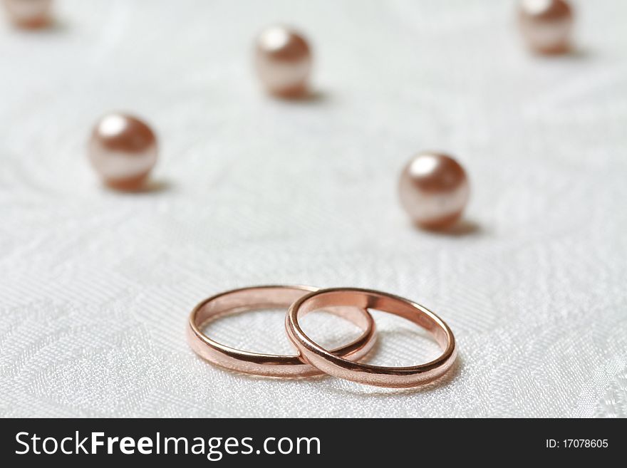 Wedding rings on lace background with pearls