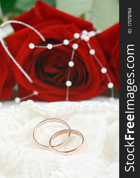 Wedding rings on lace against red rose