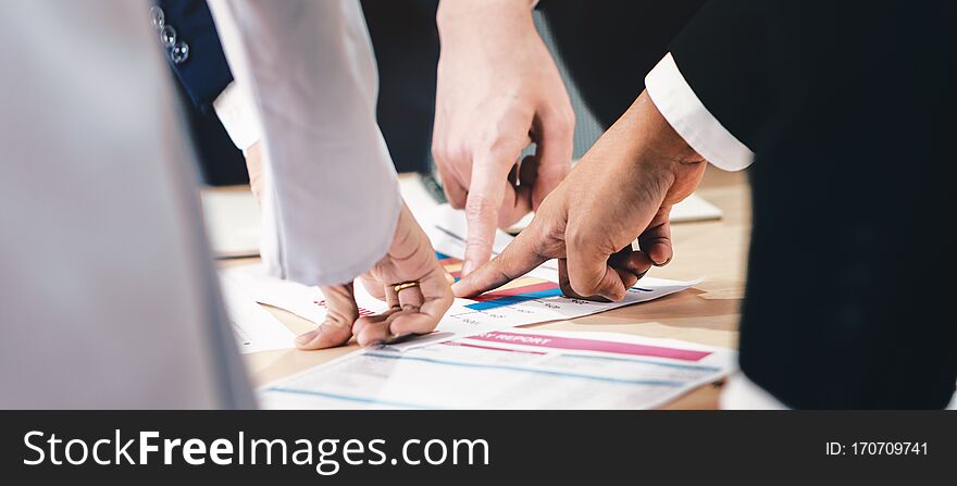 Hands and fingers of businesspeople pointing at one point on meeting table in concept of aiming together on same business target.