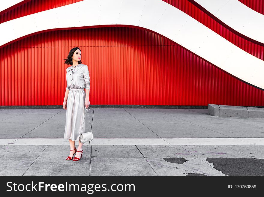 Beautiful glamorous woman in heels at the red wall