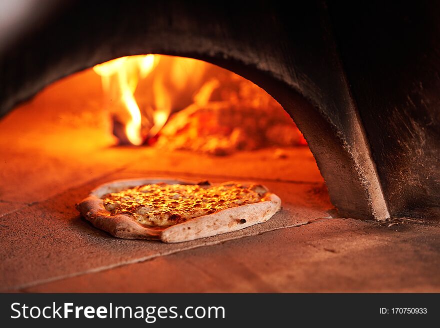 Baked tasty margherita pizza in Traditional wood oven in Naples restaurant, Italy. Original neapolitan pizza. Red hot