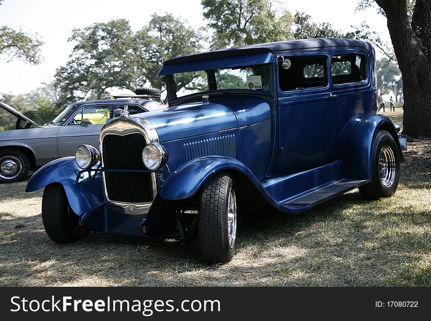 A classic blue model T parked under a shade tree near the beach at the 2010 cruisin the coast
