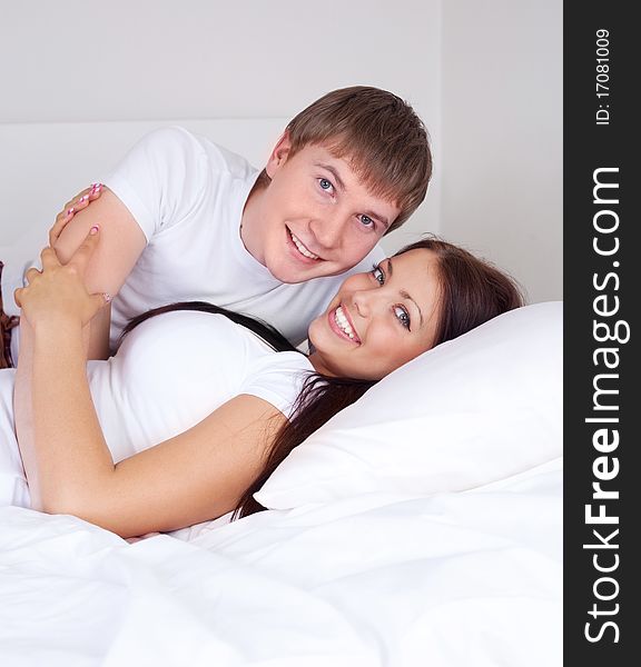 Happy young caucasian couple on the bed at home. Happy young caucasian couple on the bed at home