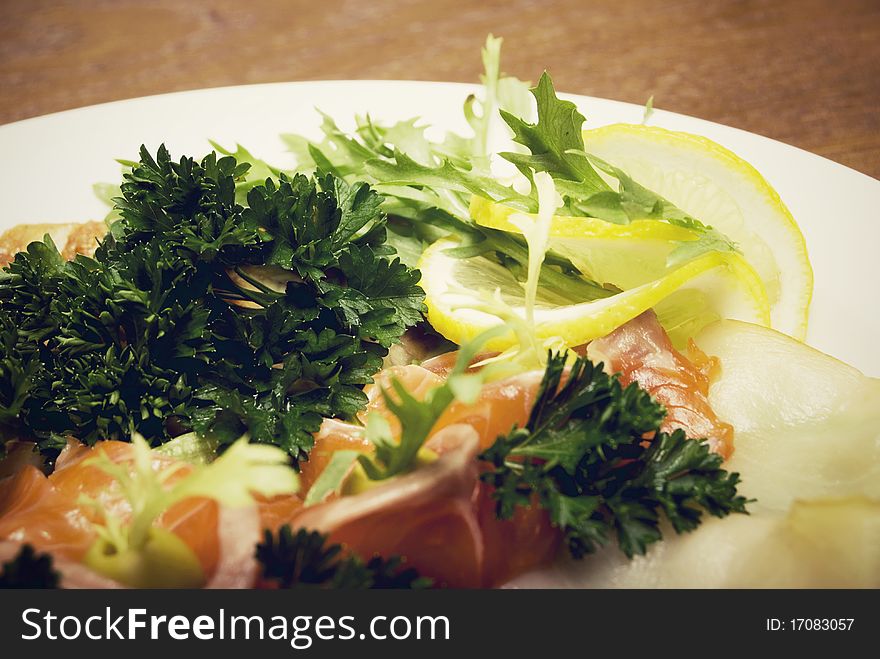 Appetizer made of meat and fish served with salad on the round plate