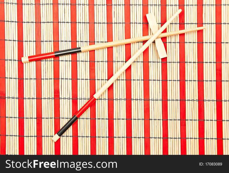 Red and black sticks for sushi on bamboo background