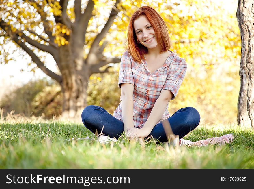 Portrait of red-haired girl in the autumn park. Outdoor shot.