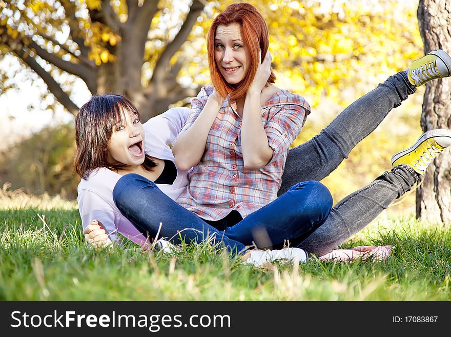 Two beautiful girlfriends at the autumn park near tree. Outdoor shot.