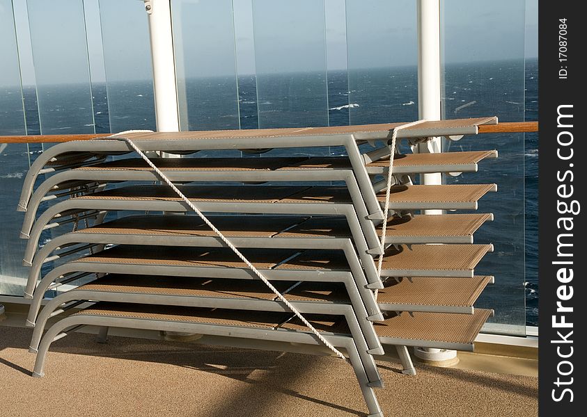 Cruise deckchairs stacked and tied in rough seas