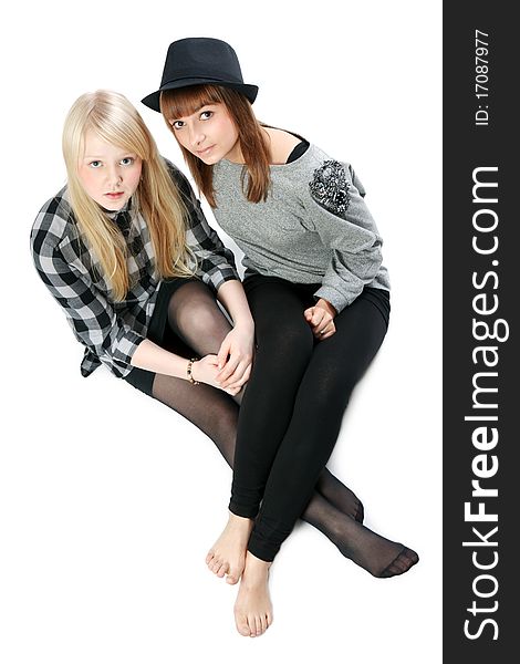 Two beautiful young girls sit on floor