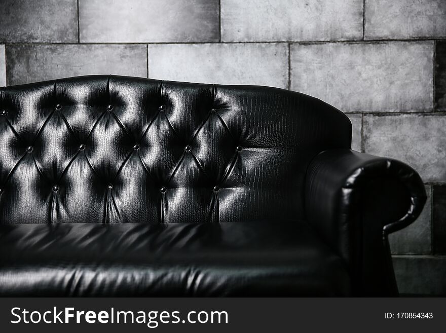 Black leather sofa against a gray stone wall
