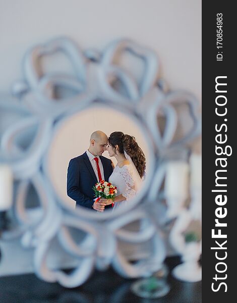 Happy bride and groom are reflected in the mirror.