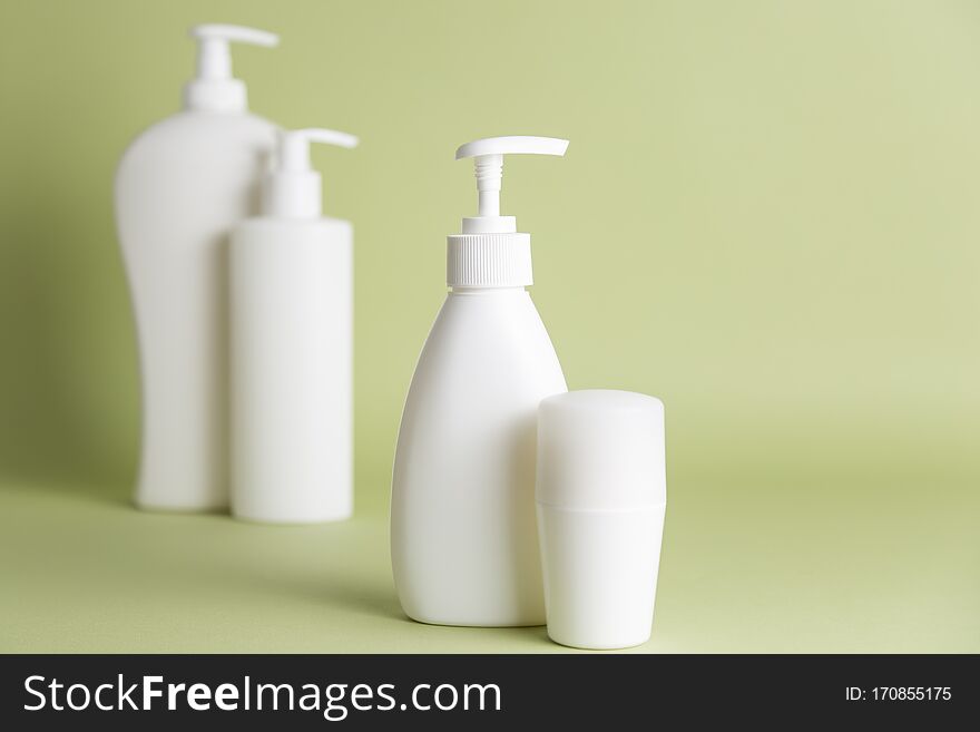 White plastic soap dispensers and deodorant on a green background. White plastic soap dispensers and deodorant on a green background.