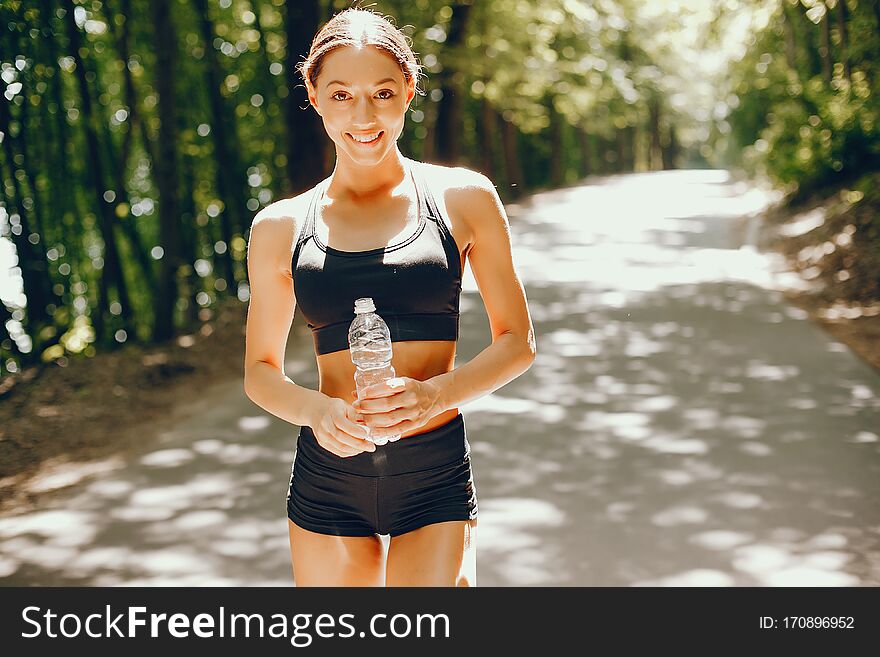 Pretty lady training in a summer park. Brunette with beauty figyre. Girl in a black top. Pretty lady training in a summer park. Brunette with beauty figyre. Girl in a black top