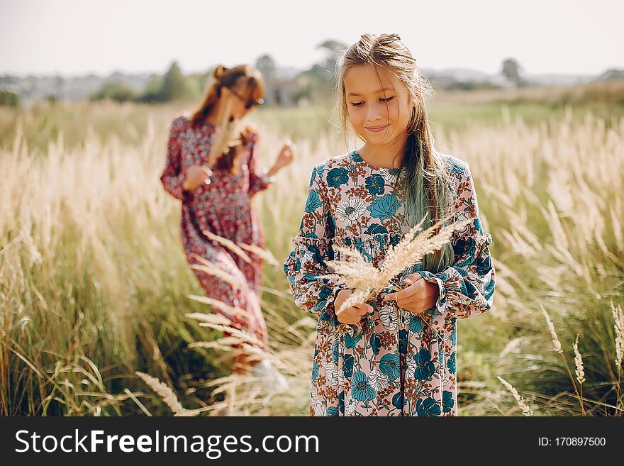 Fashionable mother with daughter. Family in a summer fiels. Girl in a red dress. Fashionable mother with daughter. Family in a summer fiels. Girl in a red dress.
