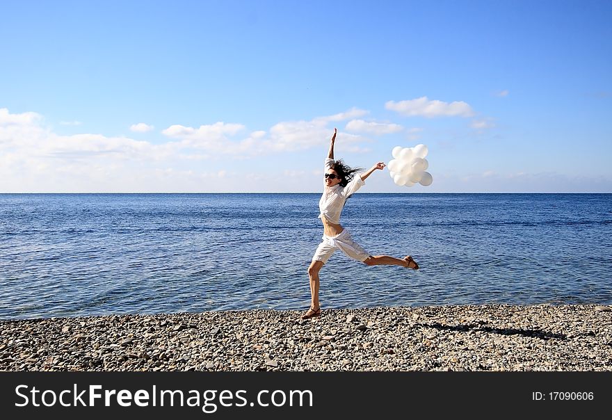 Happy young woman with white balloons on the seashore. Happy young woman with white balloons on the seashore