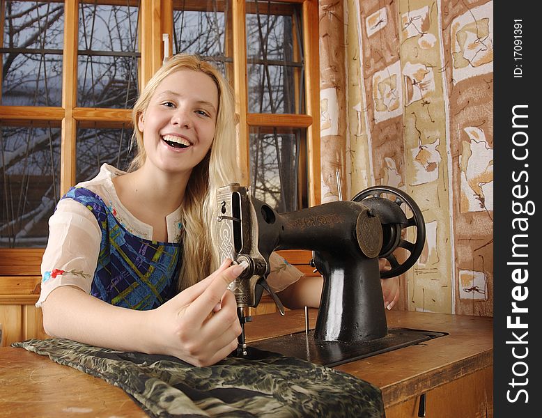 Young woman sitting at a sewing machine in the farmhouse. Young woman sitting at a sewing machine in the farmhouse.