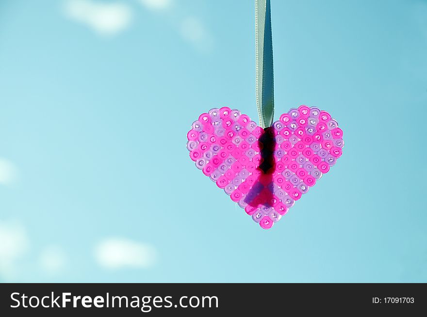 Handcrafted heart pendant to the background of blue sky