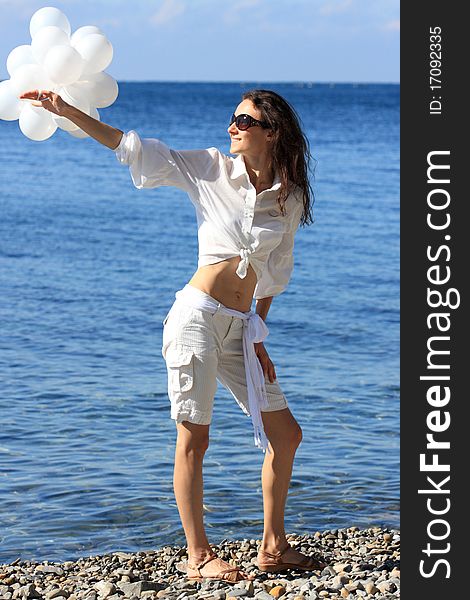 Happy young woman with white balloons on the seashore. Happy young woman with white balloons on the seashore