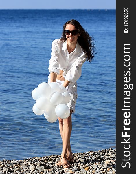 Happy young woman with white balloons on the seashore. Happy young woman with white balloons on the seashore