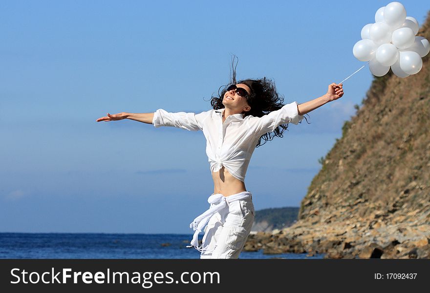 Happy young woman with white balloons on the seashore. Happy young woman with white balloons on the seashore