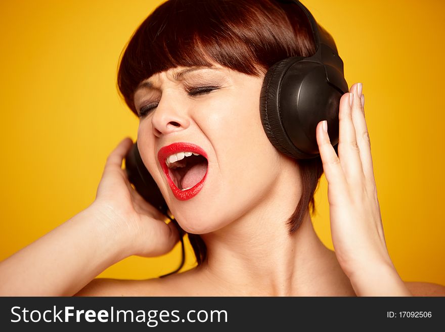 Portrait of a beautiful woman with headphones isolated on yellow