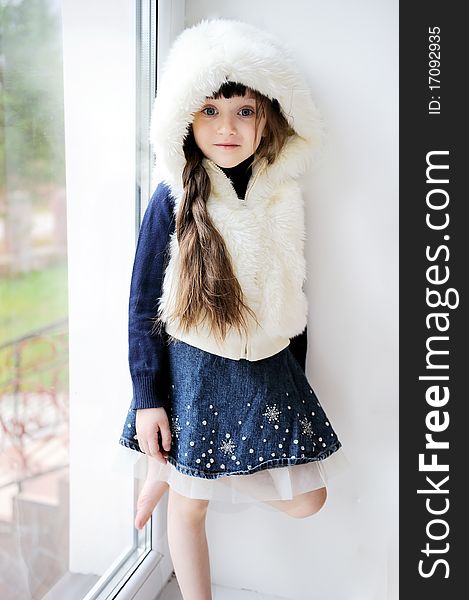 Adorable small girl in white fur hood with long dark hair and blue eyes