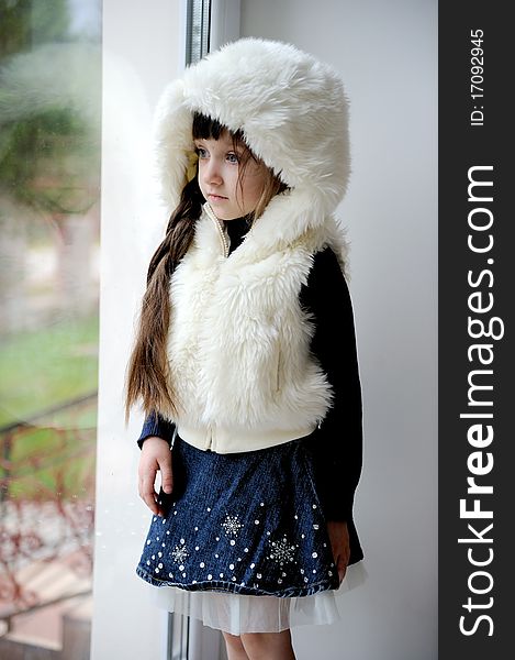 Adorable small girl in white fur hood with long dark hair and blue eyes