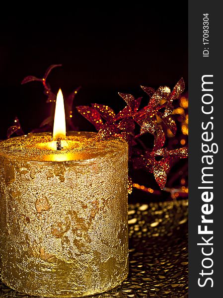 Christmas Decor, a burning candle with glossy leaves on a dark background. Christmas Decor, a burning candle with glossy leaves on a dark background.