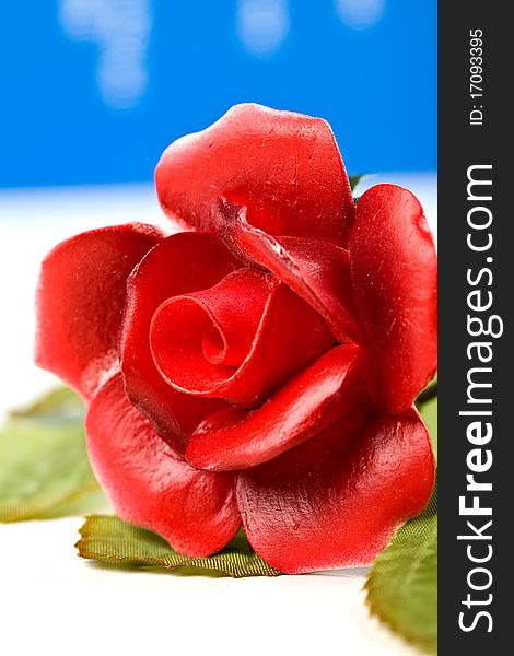 Photo of red artificial glass rose on blue background