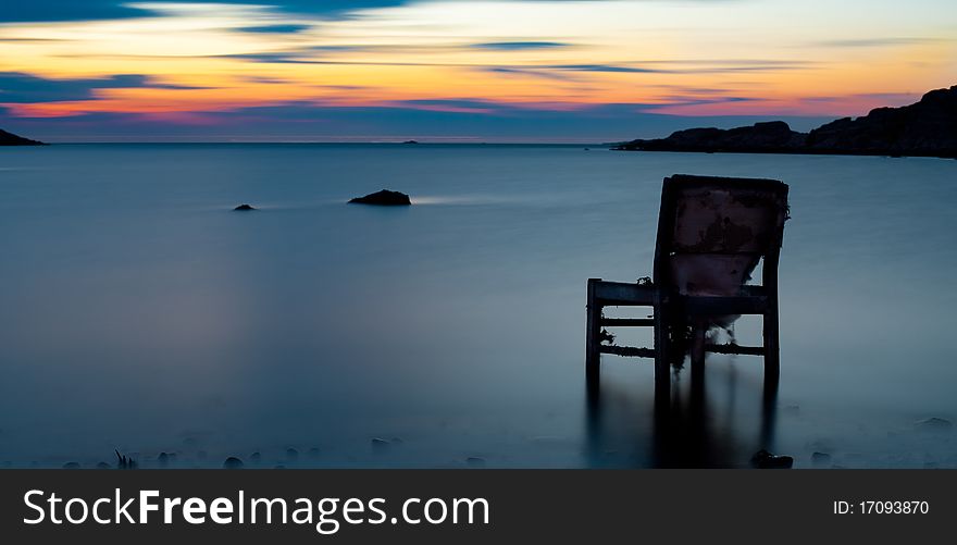 An old chair sitting in water on swedish coast. An old chair sitting in water on swedish coast