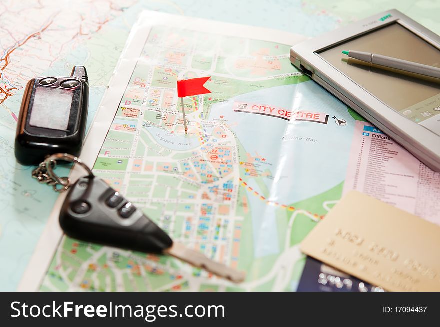 Road map with a red flag, car keys, electronic organizer and credit cards. closeup. Road map with a red flag, car keys, electronic organizer and credit cards. closeup.