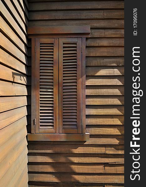 Wooden window at corner of frame house, shown as rhythmic shape, harmonious color and perspective.