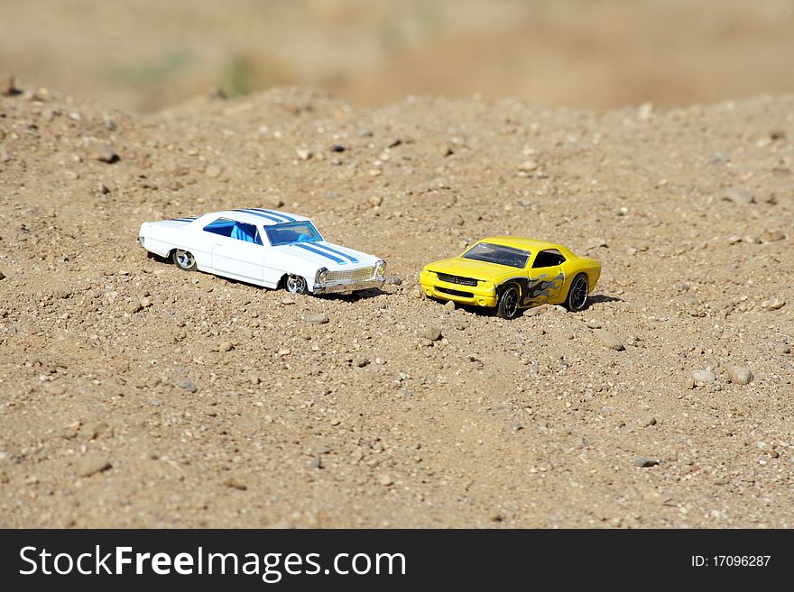 Two toy cars parked on a hill. Two toy cars parked on a hill.