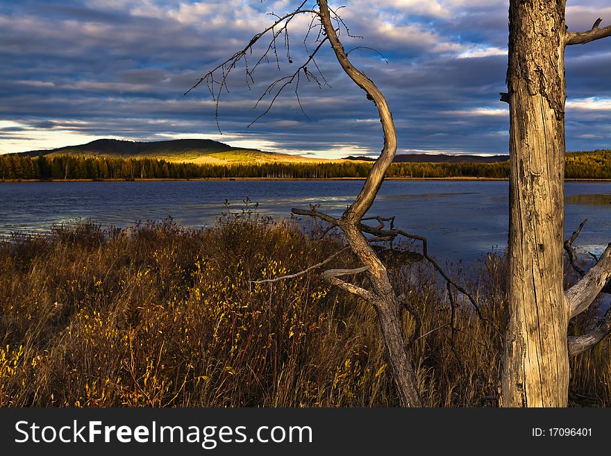 This is a picture of the sunset under the lake and forest.