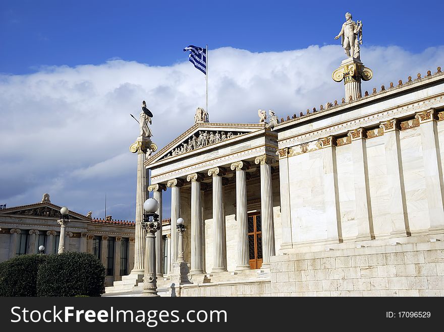 The National Academy Building in Athens. The building, which was built from 1859-1885, is located on the south of The University of Athens' main building (Panepistimio street). In front of the facade stand two high ionic columns, which bear the colossal statues of Athena (Minerva) and Apollo. The National Academy Building in Athens. The building, which was built from 1859-1885, is located on the south of The University of Athens' main building (Panepistimio street). In front of the facade stand two high ionic columns, which bear the colossal statues of Athena (Minerva) and Apollo.