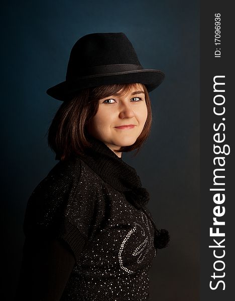 Portrait of attractive young girl in hat. Against a dark background