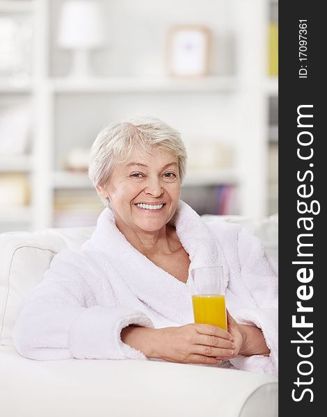 Smiling attractive woman in a bathrobe with a glass of juice. Smiling attractive woman in a bathrobe with a glass of juice