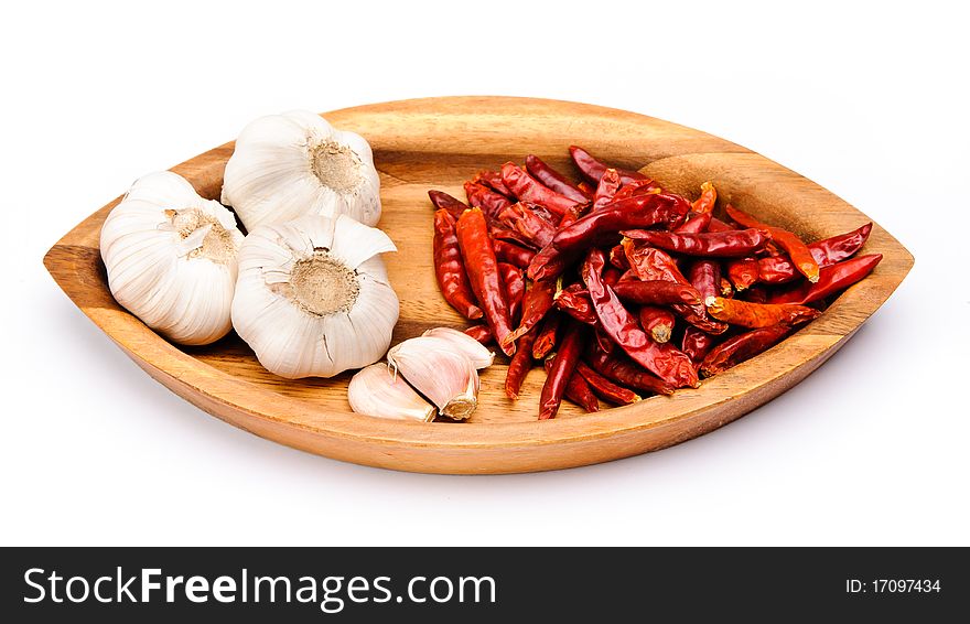 Chili fruit and some garlic on a wooden plate. Chili fruit and some garlic on a wooden plate