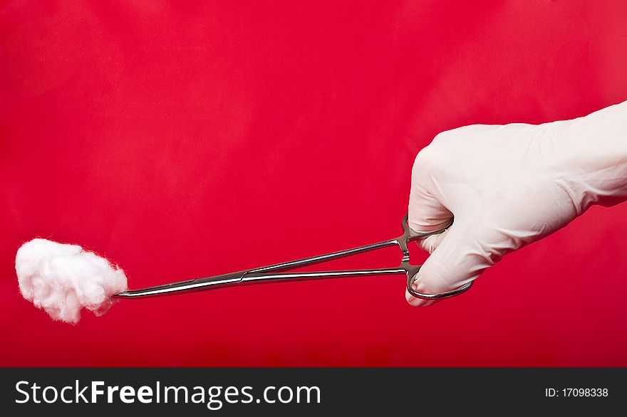 Hand with the medical instrument on a red background