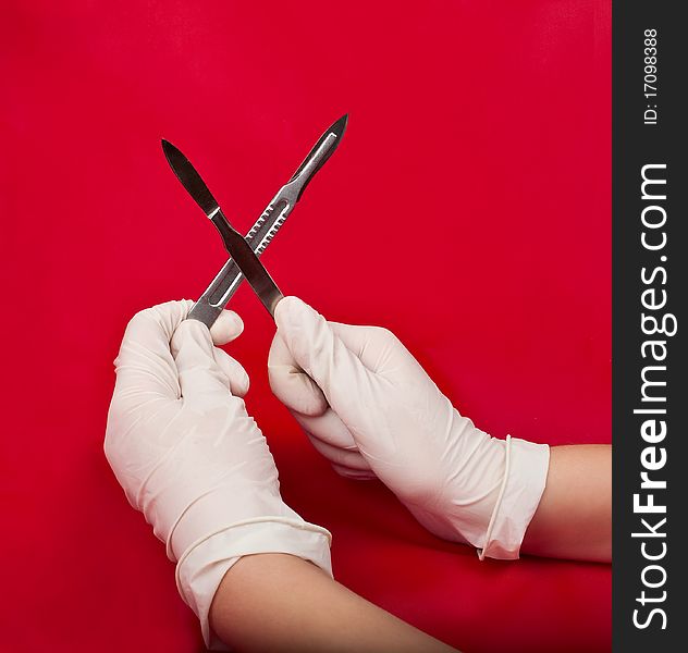 Scalpel in his hand on a red background