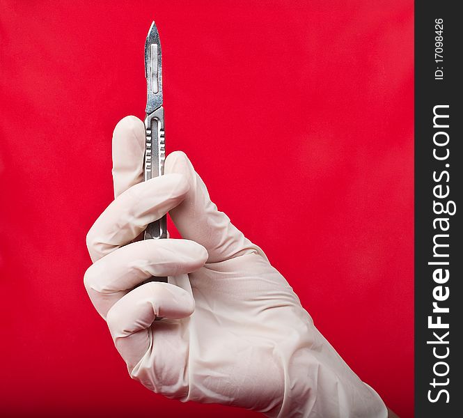 Scalpel in his hand on a red background