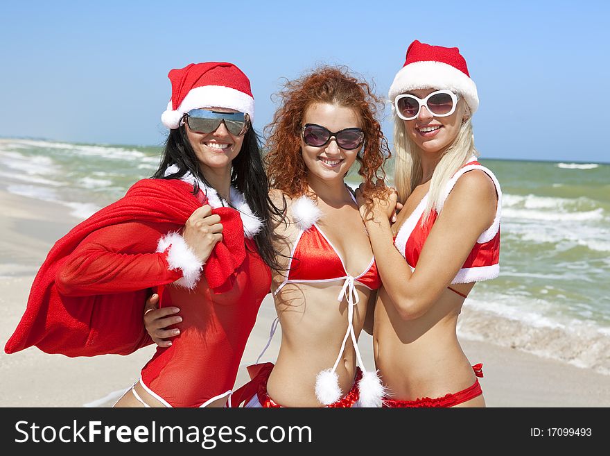 Three happy girls in Santa Clause suit having fun on the beach. Three happy girls in Santa Clause suit having fun on the beach