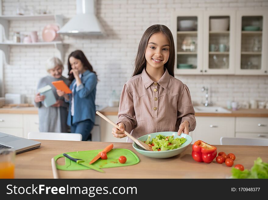 Little Girl In The Kitchen Showing Cooked Salad.