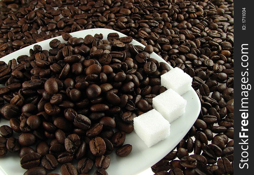 Close-up of coffee beans on the white plate with sugar. Close-up of coffee beans on the white plate with sugar