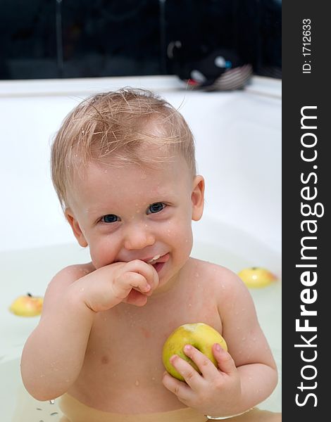 Cute little boy in the bath eating apple