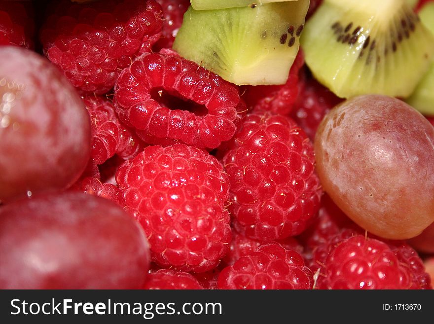 A close up of a fresh fruit salad with grapes, raspberries and kiwi.