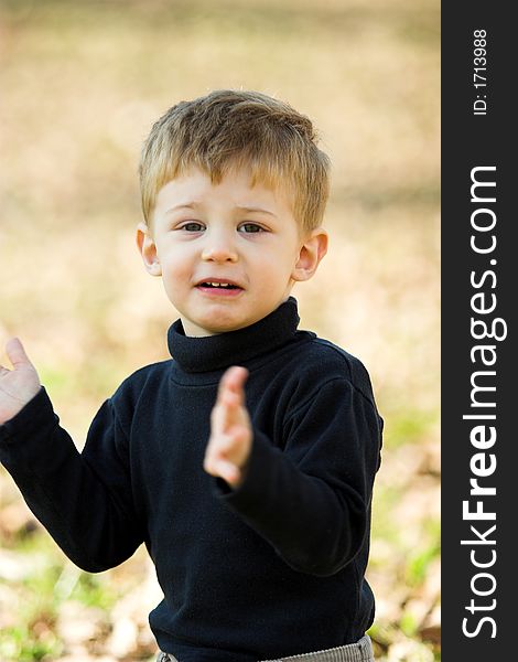 A little boy clapping in the park