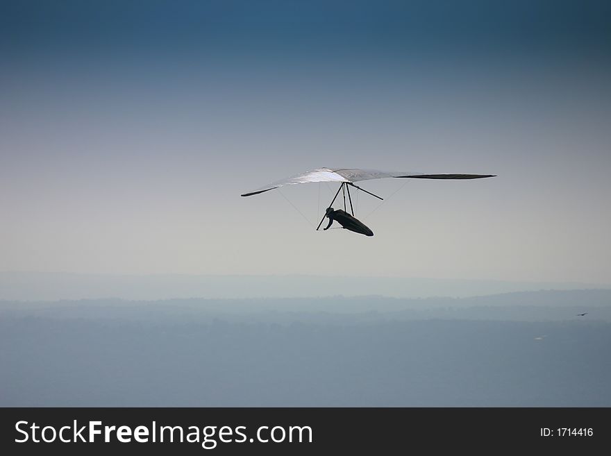 Hang glider soaring in blue sky.