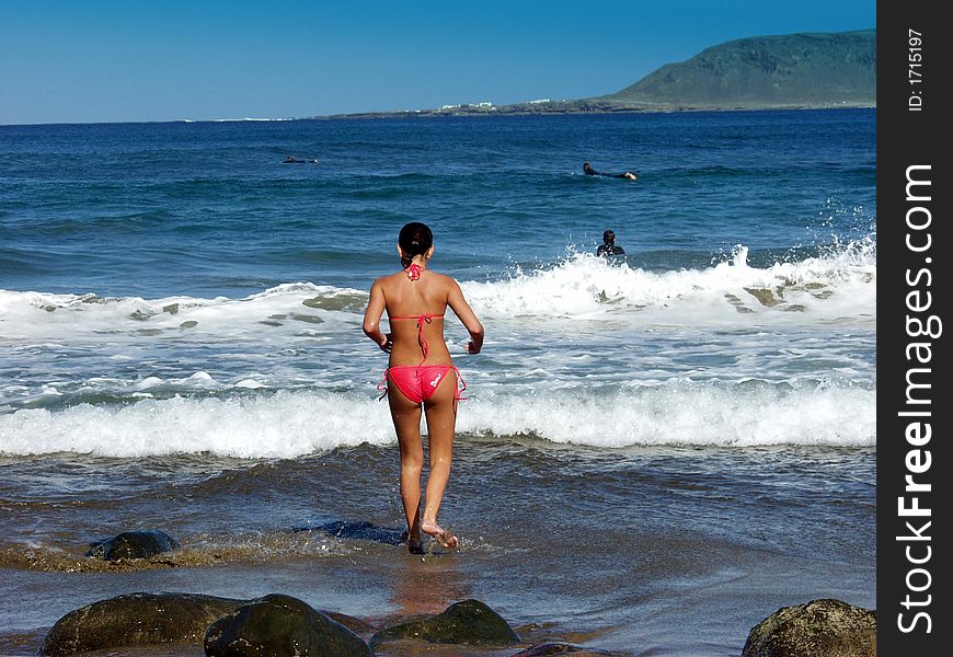 Beautiufl girl in a red bikini running into the ocean