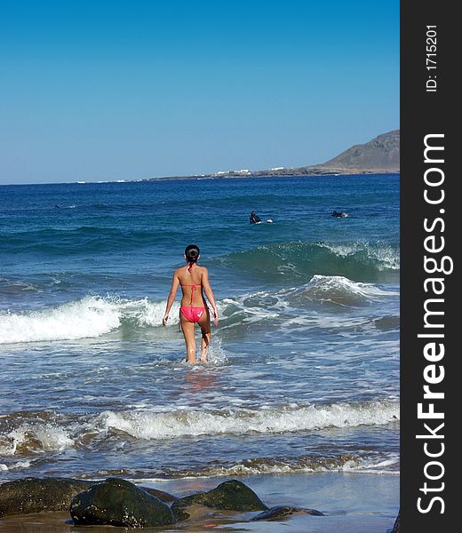 Beautiufl girl in a red bikini running into the ocean